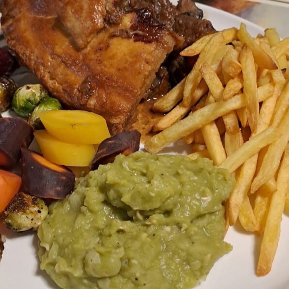 Beef and Guinness pie with mushy peas, chips, and vegetables