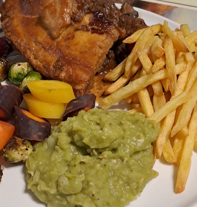 Beef and Guinness pie with mushy peas, chips, and vegetables